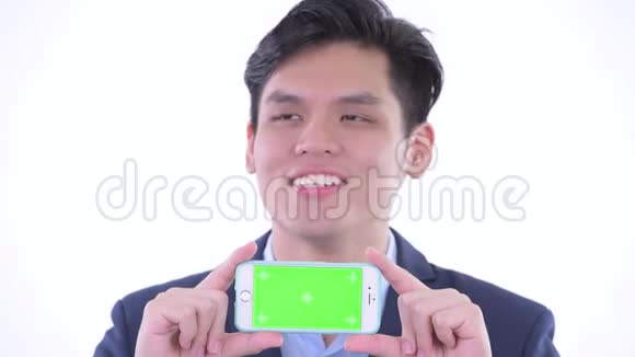 一位年轻快乐的亚洲商人一边看手机一边思考视频的预览图