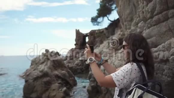 女人拍摄海洋和岩石视频的预览图