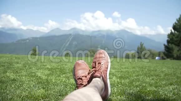 一个人的脚在草坪上放松对抗森林蓝天云和山在山上远足运动鞋视频的预览图