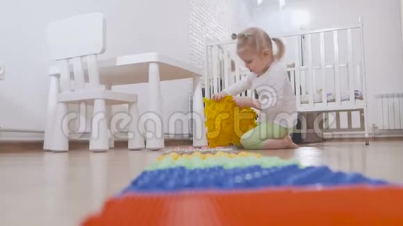 一个小孩在儿童房间里坐着玩一个多色的按摩垫视频的预览图