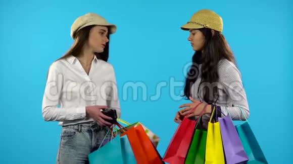 两个女孩拿着购物袋露出一个空钱包蓝色背景视频的预览图