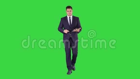 商人在他的平板电脑上走来走去看着摄像机在绿色上呈现一些东西视频的预览图
