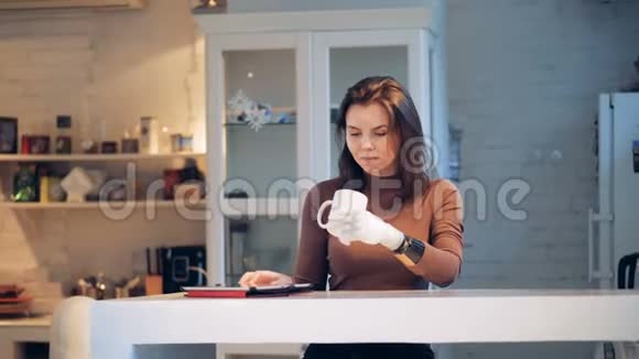 年轻的女人从桌子上拿出一块平板电脑戴着机器人的手关上了视频的预览图