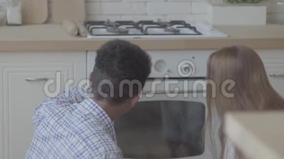 后面的女人有一头金色的长发年轻人坐在地板上看着烤箱视频的预览图
