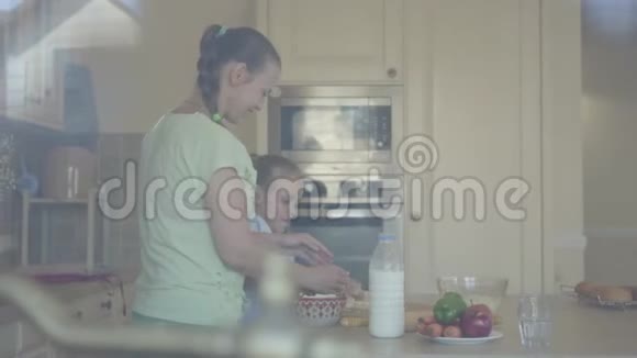 年轻的女人和小女儿在家里厨房里做蛋糕女孩和母亲用透明的面粉搅拌视频的预览图