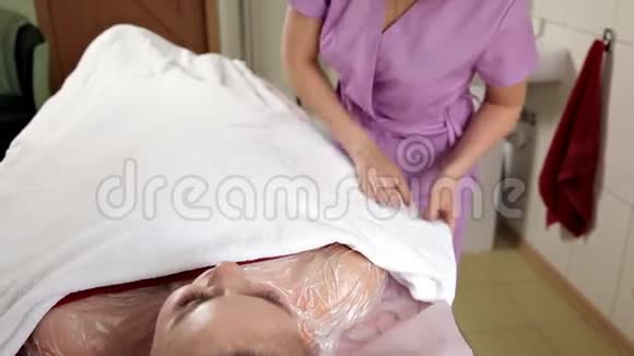 休息的一部分一位平静梦幻的女士躺在毛巾上身上戴着一个奶油面具水疗中心皮车视频的预览图