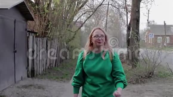 一个穿着绿色毛衣的女孩带着私人住宅兴高采烈地跑到街上的摄像机前视频的预览图