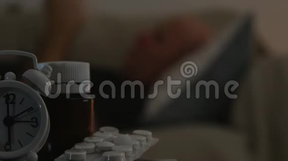 模糊的图像与痛苦的男人在床上和医疗药片在桌子上视频的预览图