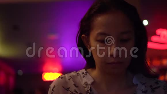 亚洲女人在夜间霓虹灯酒吧打电话视频的预览图
