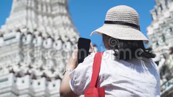 亚洲女士用智能手机给WatArun拍照动作缓慢主塔在后台视频的预览图