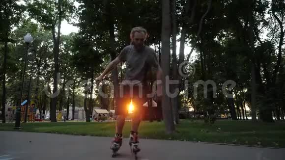 年轻的长发胡须男滑轮手正在城市公园的一个美好的夜晚跳舞自由式轮滑视频的预览图