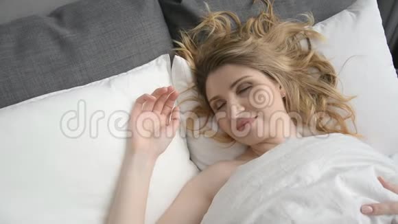 漂亮的白种人年轻女性清晨醒来然后躺着伸展身体视频的预览图