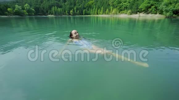 美丽苗条性感快乐的女士穿着蓝色泳装在炎热的山湖里放松游泳和享受淡水视频的预览图