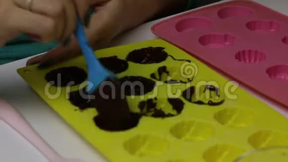 女人用刷子把液体巧克力涂成硅胶状准备釉面糖果视频的预览图