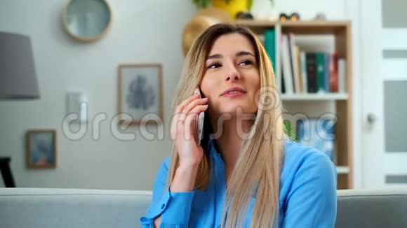 这位年轻貌美的女士坐在沙发上与一位朋友愉快地在电话中交谈视频的预览图