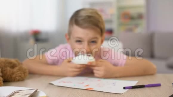 可爱的男孩坐在桌边吃奶油甜点吃糖过量糖尿病风险视频的预览图