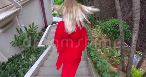 在热带酒店楼下散步的金发女孩视频的预览图