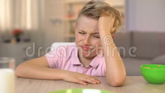 不高兴的男孩厌恶地看着燕麦片美味的食物健康的早餐视频的预览图