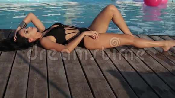 性感的女人黑发优雅的泳装在露天游泳池附近放松视频的预览图