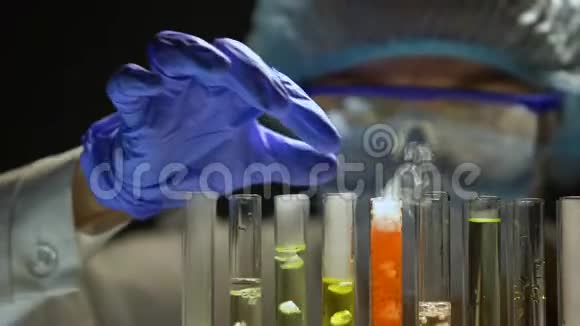 实验室助理在黑暗中用橙色液体检查试管特殊情况视频的预览图