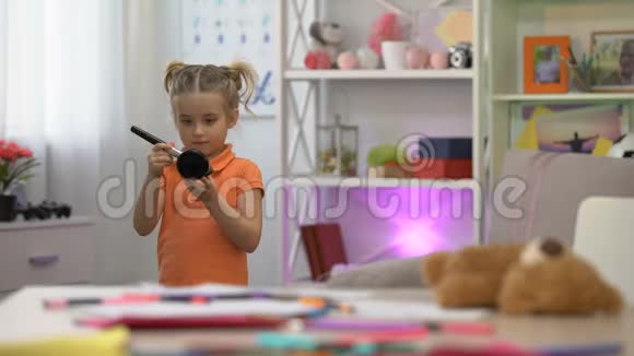 可爱的小女孩用刷子拿着镜子涂粉美梦化妆视频的预览图