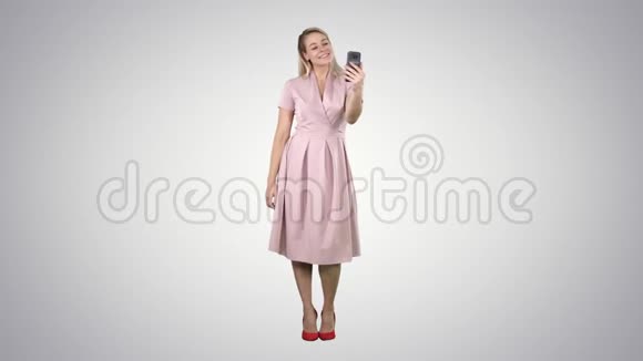 成熟女性穿着淡粉色连衣裙在渐变背景下自拍视频的预览图