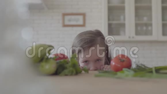新鲜蔬菜西葫芦西红柿和蔬菜放在桌子上那个可爱的小女孩从桌子上看躲了起来视频的预览图