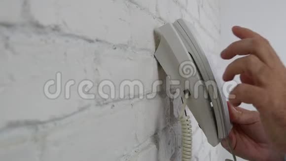 男士在办公室室内使用固定在墙上的固定电话打电话视频的预览图