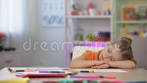 可爱的女生睡在桌子上彩色铅笔和纸桌上教育视频的预览图