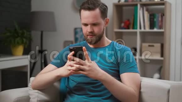 一个人在房间里手机上的应用程序中滚动饲料的特写镜头男性在智能手机上打字和发短信视频的预览图