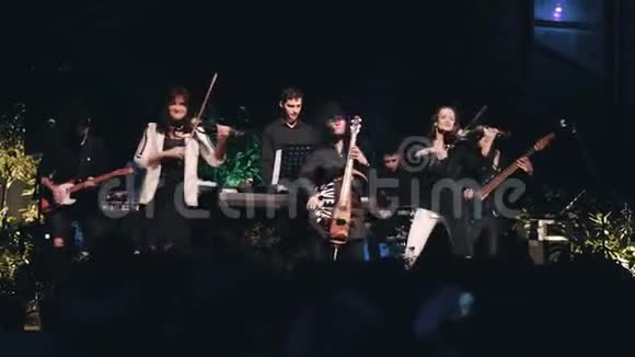 富有表现力和情感的小提琴手女孩在摇滚乐队的舞台上表演视频的预览图