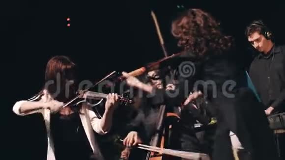 三位小提琴手在舞台上嬉戏打闹器乐合奏的出色表现很酷的摇滚乐队视频的预览图