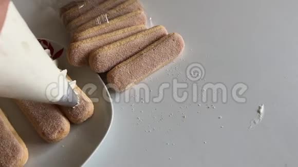 女人在萨沃亚迪饼干上做奶油玫瑰使用糕点包视频的预览图