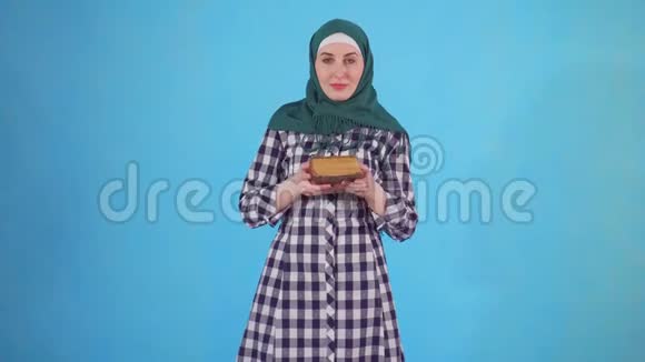 戴头巾的阿拉伯年轻女子手里拿着蓝色背景的书视频的预览图