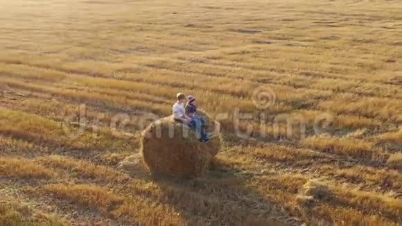 那孩子站在干草堆上挥动他的手他又玩又笑乡村日落视频的预览图