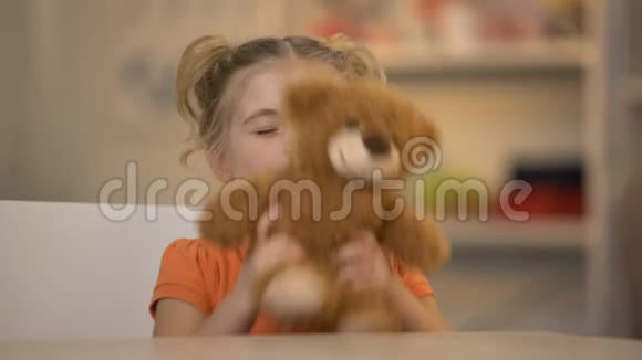 可爱的微笑女孩抱着棕色泰迪熊快乐的孩子快乐的童年视频的预览图