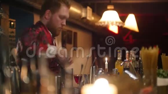 年轻的职业酒保穿着红色围裙把柠檬放进装有红色白酒的杯子里视频的预览图