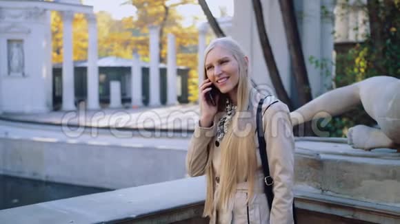 在这个城市的秋天公园里一个快乐的女孩正在用手机说话视频的预览图