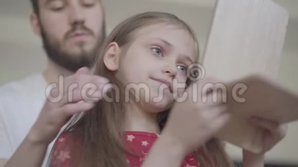 小胡子的父亲把皇冠戴在小女孩的头上让她成为公主而孩子则看着她视频的预览图