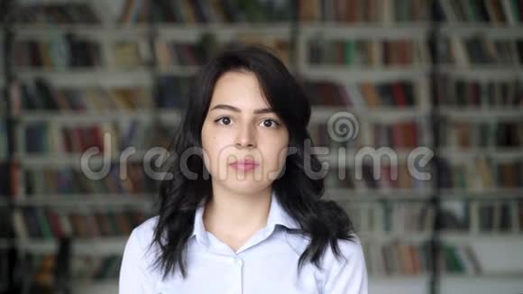 图书馆书架背景上的亚洲年轻女子特写画像视频的预览图