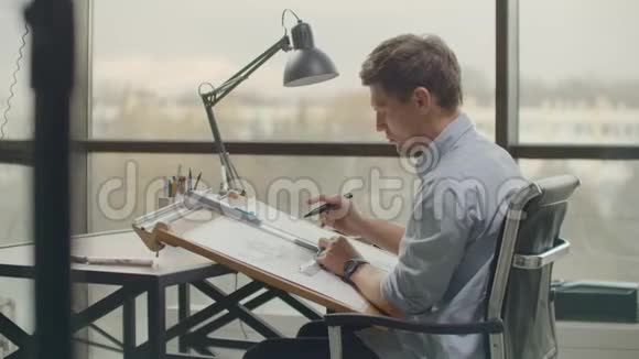 建筑师站在设计蓝图的工作中在家庭办公室的木桌上描绘一个建筑项目建筑视频的预览图