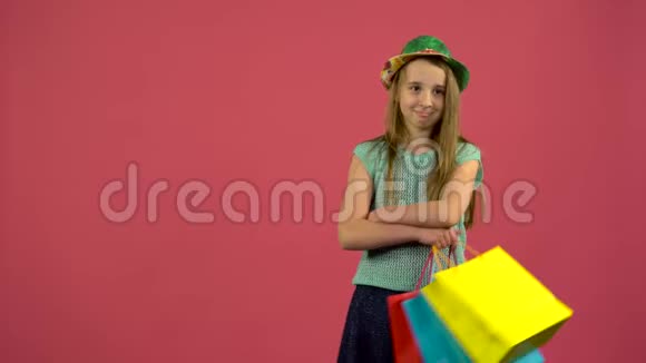 手里拿着购物袋的孩子看上去很直粉色背景视频的预览图