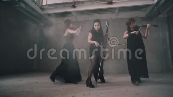 三位女小提琴手在烟雾弥漫的房间里演奏很棒的表演视频的预览图