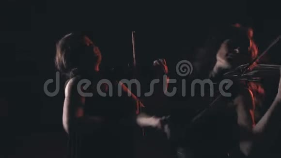 两个令人惊叹的小提琴手女孩在亲密的灯光下进行情感演奏不错的特写视频的预览图