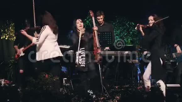 有魅力的女大提琴演奏家在舞台上表演和舞蹈作为一个凉爽的摇滚乐队的一部分艺术女孩视频的预览图