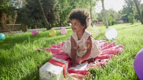 快乐的非洲小女孩在公园里画着五颜六色的气球背景视频的预览图