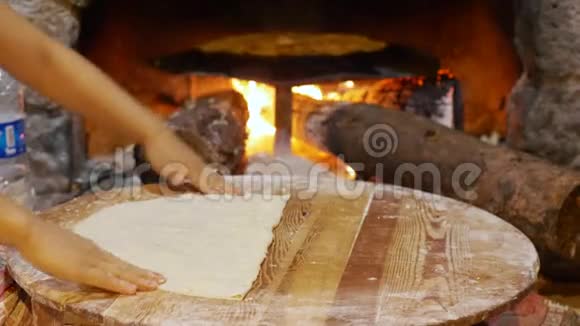 女性用手在壁炉背景的木桌上煮面团女人煮传统的土耳其菜视频的预览图