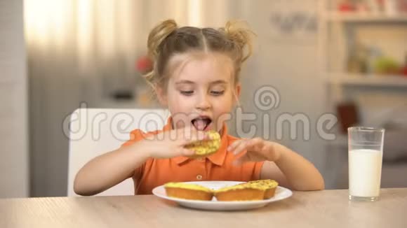 女孩子吃美味的甜甜圈桌上的牛奶杯甜食营养视频的预览图