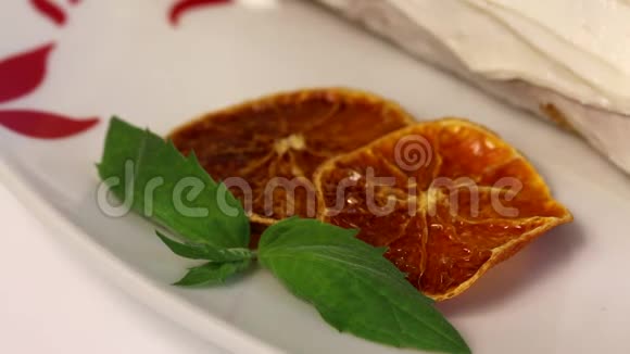海绵奶油蛋糕涂上奶油用干橙片和新鲜薄荷叶装饰特写镜头视频的预览图