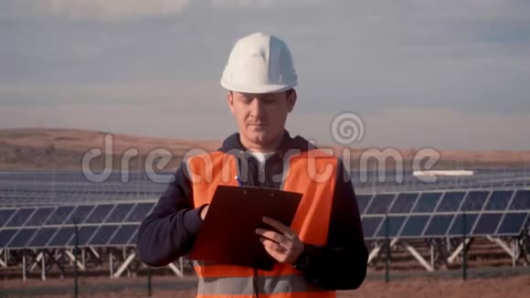 穿着白色头盔和橙色背心的工程师在太阳能领域注意到一些东西并制作了一个铅笔素描视频的预览图